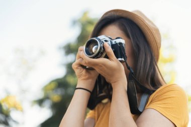 Genç kadın parkta fotoğraf çekmek için bir kamera ile.