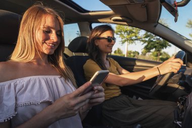 Güzel kadın onun mobil kullanarak bir arkadaşıyla bir araba.