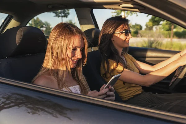 美人彼女の携帯電話を使用する友人と車の運転 — ストック写真