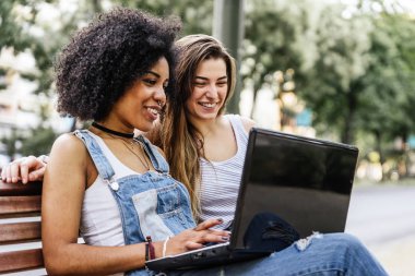 Güzel kadınlar sokakta bir dizüstü bilgisayar kullanarak. Gençlik kavramı.