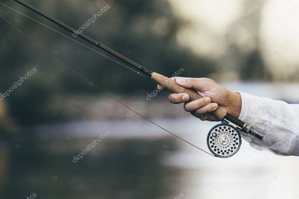 Fly fishing rod in fisherman hand.