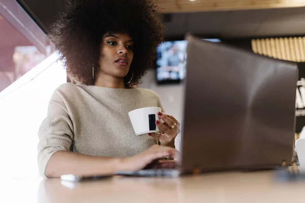 Portrait of attractive afro woman using laptop at the coffee shop. Business woman concept