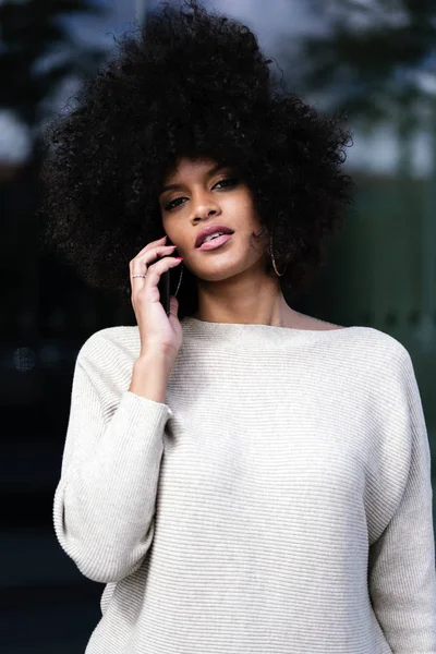 Portrait of attractive afro woman using mobile phone in the street. Business woman concept