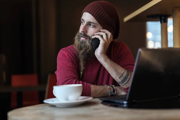 Örgülü Sakallı Kafede Kahve Telefonla Konuşurken Sahip Dizüstü Bilgisayar Ile — Stok fotoğraf
