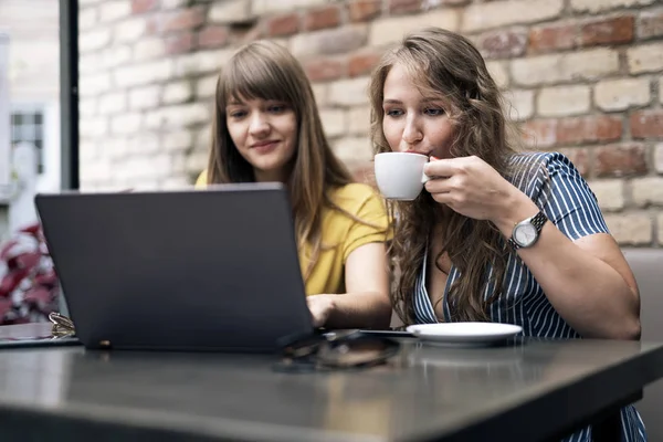 フレンドリーなノート パソコンを使用している間会談コーヒーのカップを持っているスタイリッシュな若い女性 — ストック写真