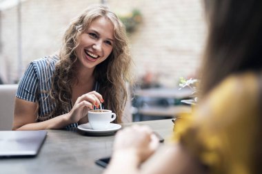 Masada oturan ve sohbet ederken samimi toplantı bardak kahve ile şık genç kadın