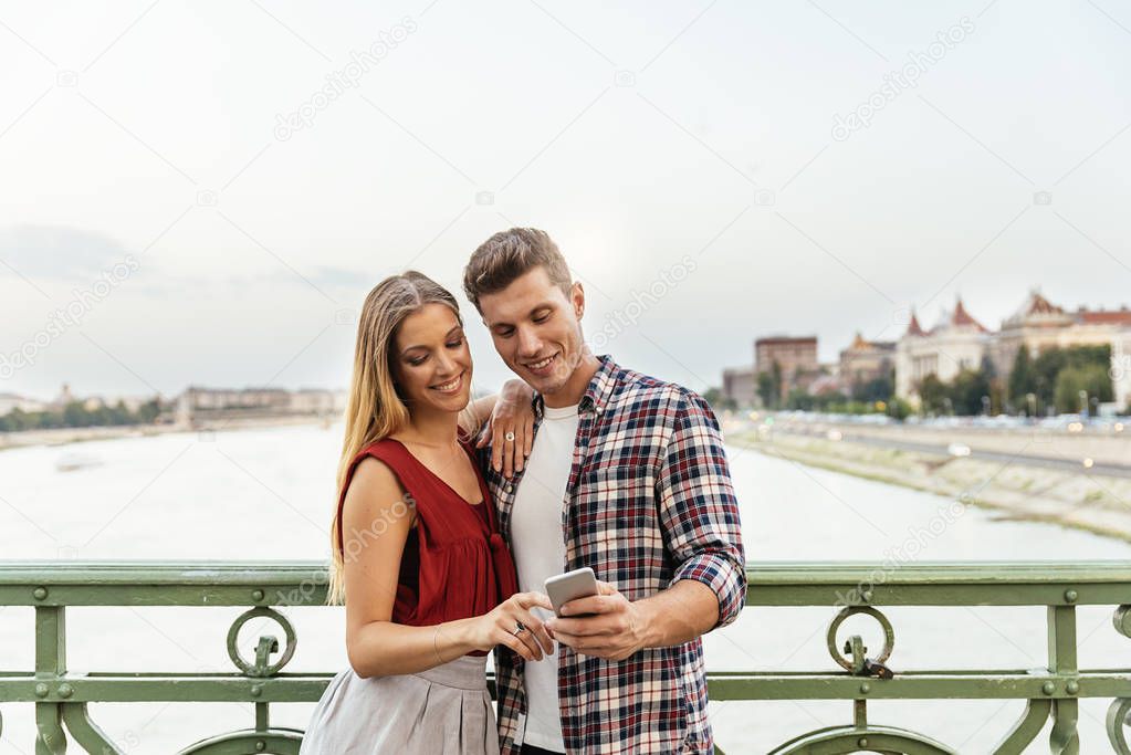 Portrait of young couple using mobile phone in the street. Mobile Concept.