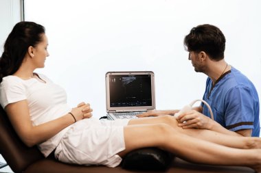 Physiotherapist giving knee therapy to a woman clipart