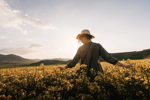 Onherkenbaar doordachte vrouw wandelen tussen bloemen op het platteland. Melancholie-concept — Stockfoto
