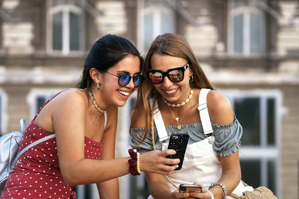 Charming female tourists messaging on smartphones outside — Stock Photo, Image