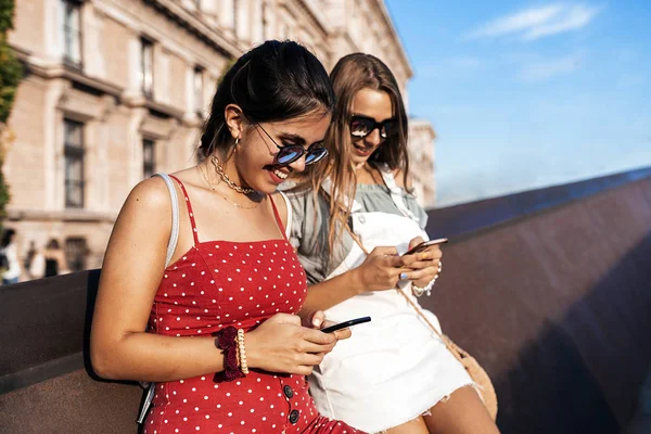 Encantadora mujer turistas mensajería en los teléfonos inteligentes fuera — Foto de Stock