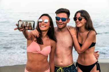 Okyanus kıyısında sahil sahilinde birlikte selfie çeken genç arkadaşlar