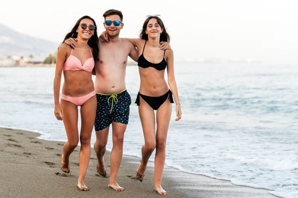 Abrazando amigos caminando juntos en la playa de arena — Foto de Stock