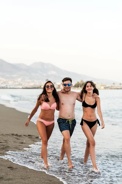 Abrazando amigos caminando juntos en la playa de arena — Foto de Stock