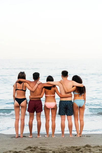 Jóvenes amigos abrazándose en la playa espumosa — Foto de Stock