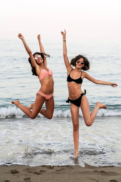 Des femmes riantes sautant sur la plage de l'océan — Photo