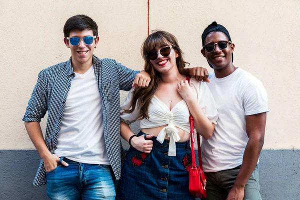 Multiracial trendy people in sunglasses embracing nearby wall — Stock Photo, Image