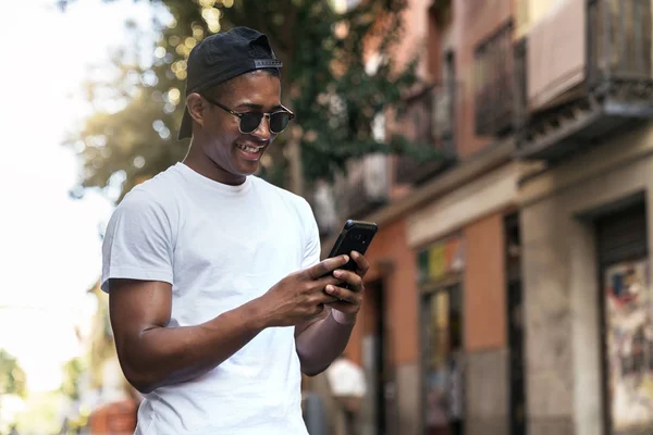 Homem preto em óculos de sol olhando para o smartphone — Fotografia de Stock