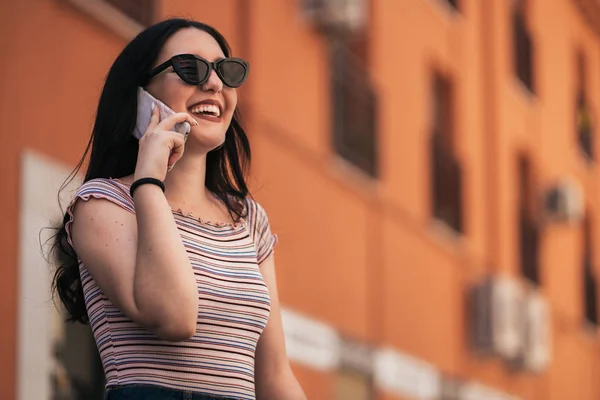 都会的なスマートカジュアルかなり若い女性がスマートフォンで話しています。携帯電話で話す幸せな女性の大人. — ストック写真