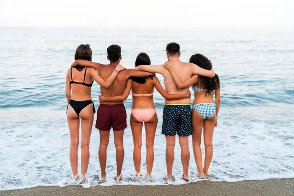 Jóvenes amigos abrazándose en la playa espumosa — Foto de Stock