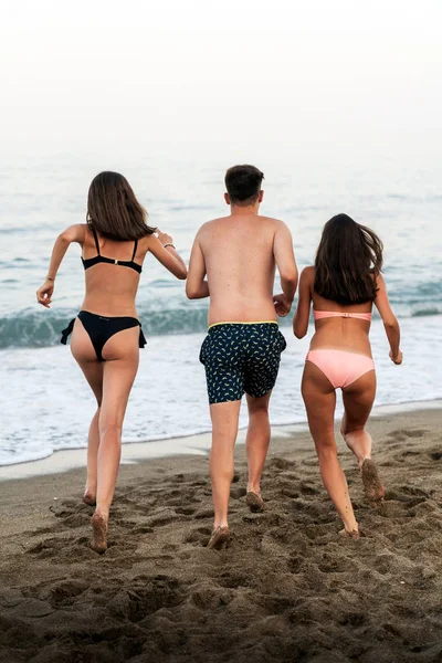 Felices amigos se topan con olas en la playa — Foto de Stock