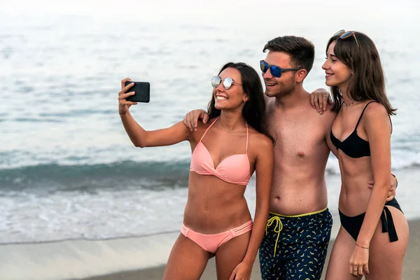 Jóvenes amigos tomando selfie en la playa junto al mar — Foto de Stock
