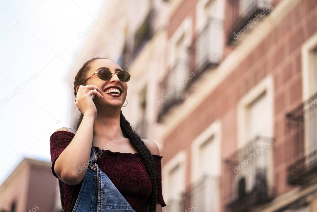 Urban smart casual pretty young woman talking on smartphone. Hap