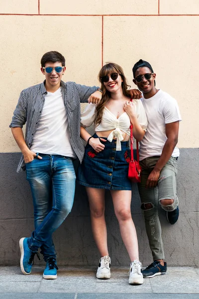 Multiraciale trendy mensen in zonnebrillen omarmen nabijgelegen muur — Stockfoto