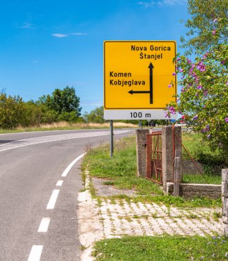 Stanjel, Slovenya - 27 Temmuz 2025: Slovenya 'da Nova Gorica ve Stanjel' i gösteren yol tabelası, kırsal alan ve açık mavi gökyüzü.