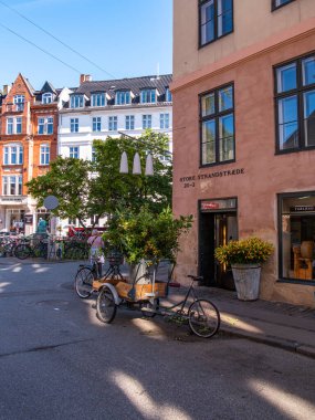 Kopenhag, Danimarka - 7 Eylül 2025: Renkli binalarla çevrili, bisikletli ve ağaçlı sakin bir sokak köşesi.