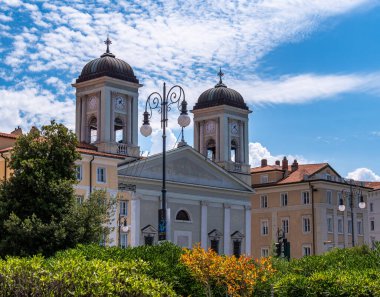 Trieste, İtalya - 1 Ağustos 2025: Mavi gökyüzünün altında ikiz çan kuleleri bulunan tarihi kilise.