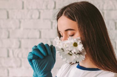 Tıp maskeli, çiçek ve koruyucu eldivenli güzel dindar kadın portresi Coronavirus COVID-19 için Tanrı 'ya dua ediyor. Yaz maskeli sadık bir genç kız. Dua eden eller