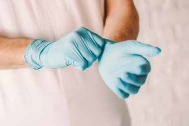 Profesyonel doktorların mavi lateks eldivenleri giyip yakın plan çekimleri. Elinde steril koruyucu eldiven olan bir adam. Kişisel koruma. Hastanın tıbbi muayenesi. Coronavirus COVID-19