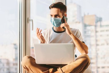 Genç işadamı, dizüstü bilgisayarla pencere eşiğinde otururken akıllı telefondan konuşuyor. Öğrenci serbest yazar evden çalışırken cep telefonuyla konuşuyor. Bilgisayarla uzaklık görevi