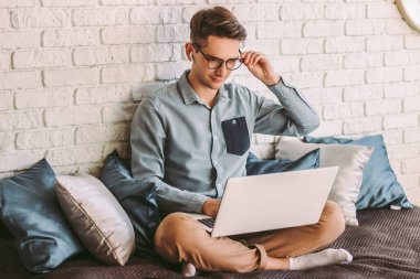 Genç hippi öğrenci gözlük takarken dizüstü bilgisayarla kanepeye uzaklık eğitimi veriyor. Şık, zeki bir işadamı, bilgisayarla çalışıyor, evde internet sörfü yapıyor. Uzak iş yaşam biçimi