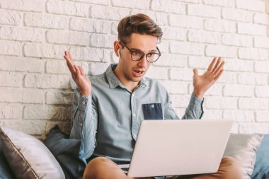 Genç şaşkın işadamı dizüstü bilgisayara bakar ve heyecanlanır, kanepeye oturur. Gözlüklü hippi bilgisayar kullanırken şok oluyor. Vay canına, duygular açık. İndirim, indirim, online alışveriş.