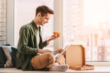 Mutlu iş adamı bir dilim lezzetli pizza yer, evden uzakta çalışır. Genç hippi serbest yazar, pencere kenarında oturur, uzak eğitim için dizüstü bilgisayar kullanır, çalışır, çalışır, çalışır, yemek yer, İtalyan yemeği yer.