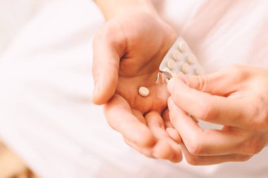 Beyaz yuvarlak haplarla dolu erkek ellerine yakın çekim. Hasta adam Coronavirus COVID-19 semptomları için oral ilaçlar alıyor. Uyuşturucu bağımlılığı. Vitamin ya da ağrı kesici alan bir adam. Haplar hazır.