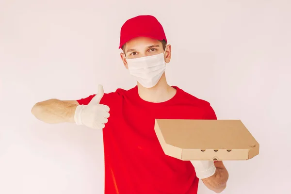 Portrait happy man italian fast food delivery service employee in medical face mask and protective glove hold cardboard pizza box and gesture thumb up. Young delivery guy carry takeaway pizza in hand