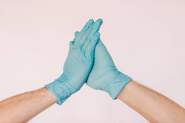 Two doctors surgeons clapping hands in blue medical gloves isolated on white background. Male hands in latex protective gloves bumping palms. New safe COVID-19 greeting, handshake, social distance