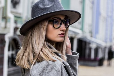 Güzelliğine güveniyordu. Paltolu, şapkalı, el ele tutuşmuş ve dışarı bakarken yüzünü çeviren şık bir genç kadın. Şık bir kız şehirde yürüyor..