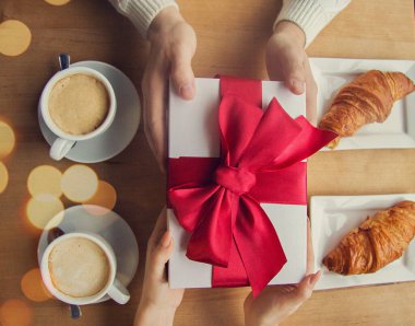 Güzel kız arkadaşına kırmızı kurdeleli hediye kutusunu veren adamın en iyi görüntüsü. Erkek arkadaşından hediye alan yakın plan bir kadın. Fransız kafesinde kutlama yapan mutlu bir çift. Tatil konsepti sunar