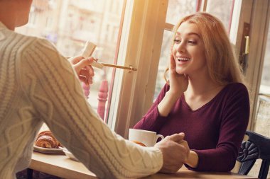 Evlen benimle! Arkaya bakan genç bir adam samimi Fransız kafesinde sevgili kız arkadaşına evlenme teklif ediyor. Romantik bir adam nişan yüzüğünü elinde tutuyor ve mutlu bir kadına sunuyor. Nişanlı çift