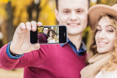 Her anı yakalıyor. Genç ve neşeli bir adamın güzel kız arkadaşıyla telefonda selfie çekerken görüntüsü. Güzel bir çift dışarıda selfie çekiyor. Birbirine aşık çift.