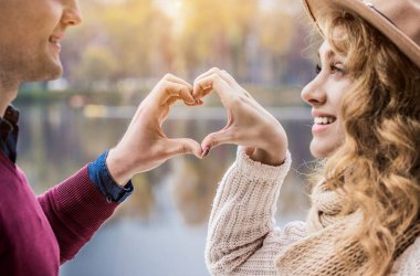 Saf aşk. Yakışıklı bir adam ve güzel bir kadının kırpılmış görüntüsü elleriyle kalp şeklini aldı. Kalp sembolü gösteren genç bir çift. Aşk ve birliktelik kavramı. Birbirine aşık çift.