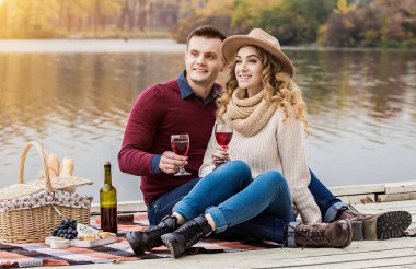 Dışarıda mutlu bir çift. Genç bir çiftin şarap içip, sırıtırken ahşap iskelede yan yana oturduğu yatay bir sahne. Yakışıklı bir adam kız arkadaşını kucaklıyor. Aşık çift romantik bir akşam yemeği yiyor.