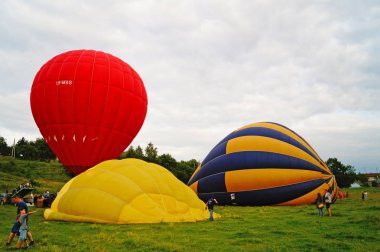 Yeşil bir glade üzerinde gökyüzüne tırmanmadan önce kırmızı, mavi, sarı, açık yeşil ve turuncu balonlar şişirmek