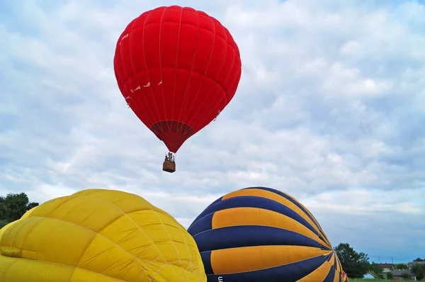 浅绿色和橙色气球在爬入绿色角上进入天空之前膨胀 — 图库照片