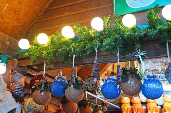 Christmas tree decorations made of glass, wood and fabric of different shapes and colors on the counter at the festive fair