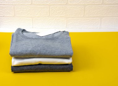 Koyu Gri, Gri ve Beyaz Tişörtler Parlak Sarı Arkaplanda.